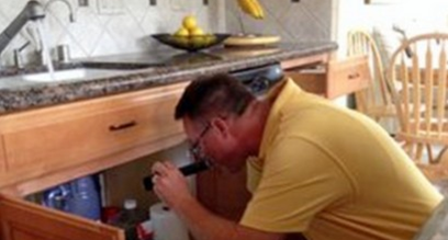 person inspecting kitchen plumbing